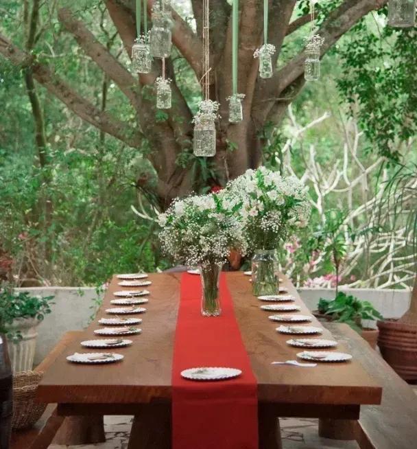 Outdoor table set under the trees with white flower arrangements