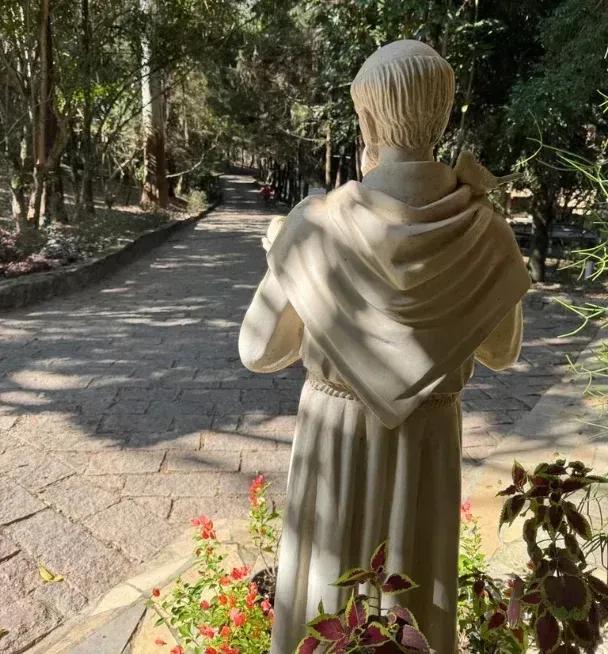 Statue of Saint Francis seen from behind, facing a stone path